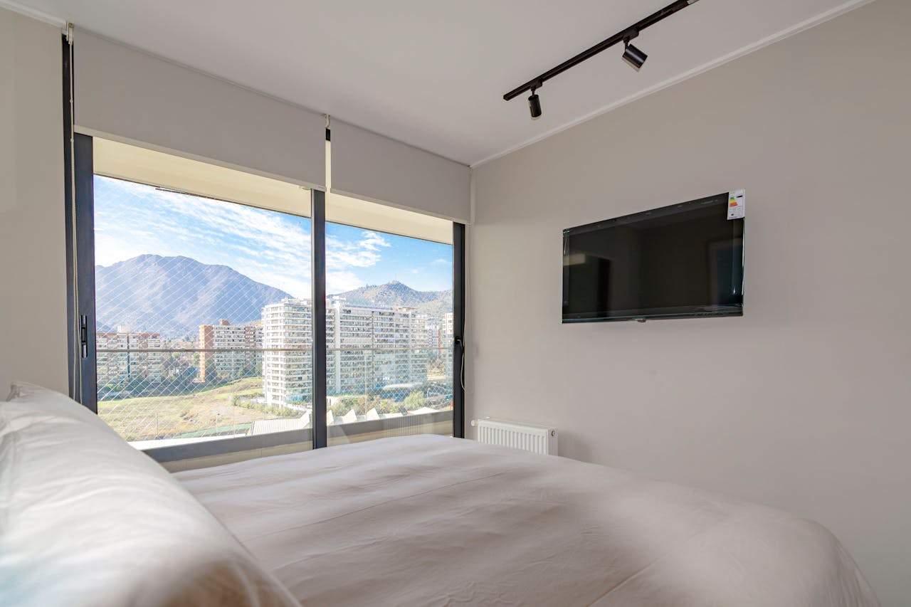 heros-img Cozy bedroom interior with a stunning mountain view and wall-mounted TV.